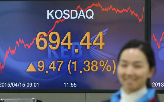 코스닥 지수가 694.44로 장을 마감한 15일 오후 서울 중구 외환은행 본점 딜링룸에서 딜러가 밝은 표정으로 종가가 뜬 스크린 앞을 지나고 있다.
